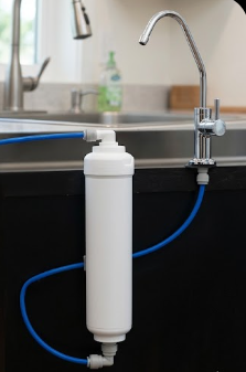 Water filtration system attached to a kitchen sink with blue tubing.