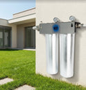 Water filtration system mounted on a house exterior with grass and building in the background