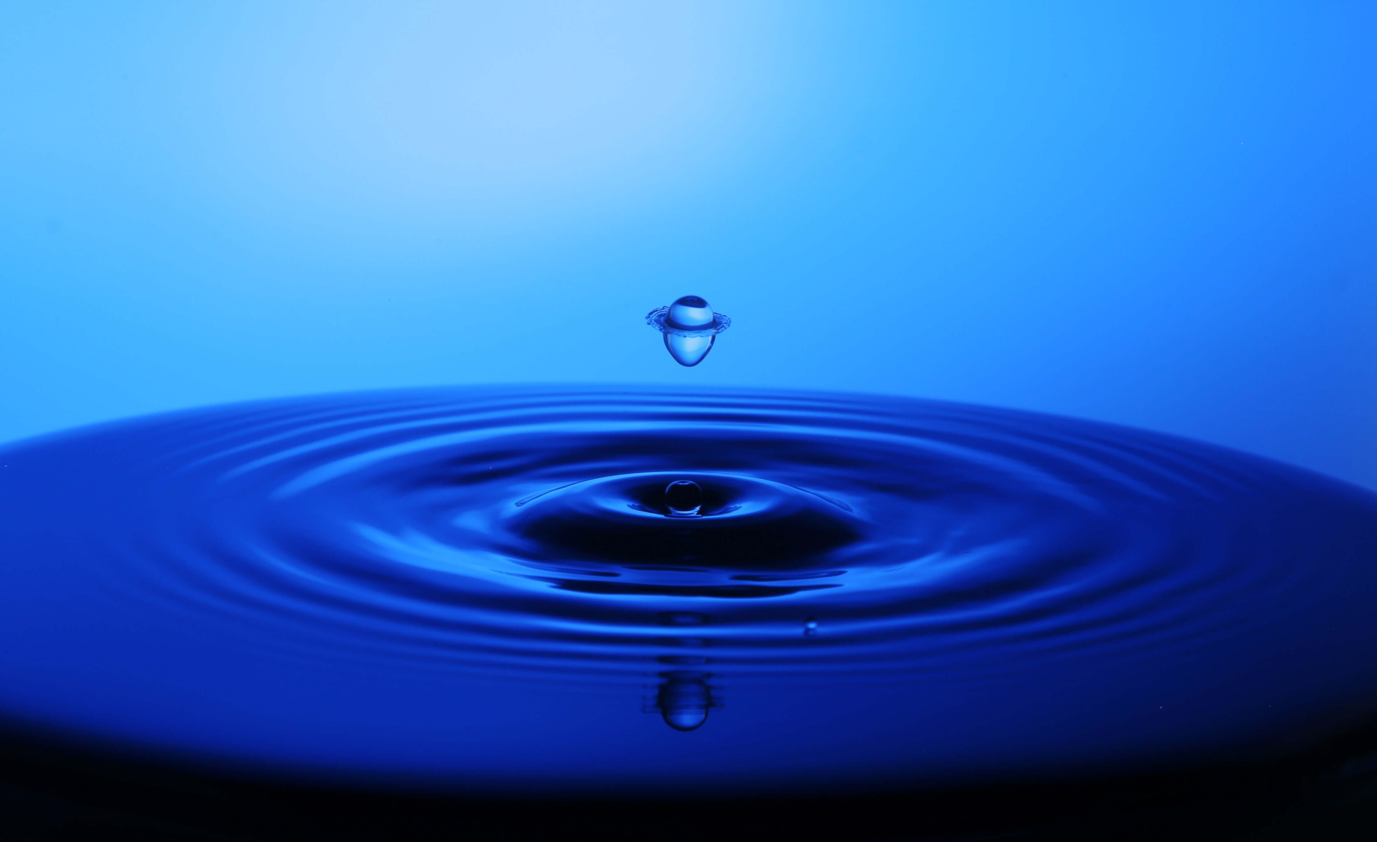 water droplet leaving ripples in blue water